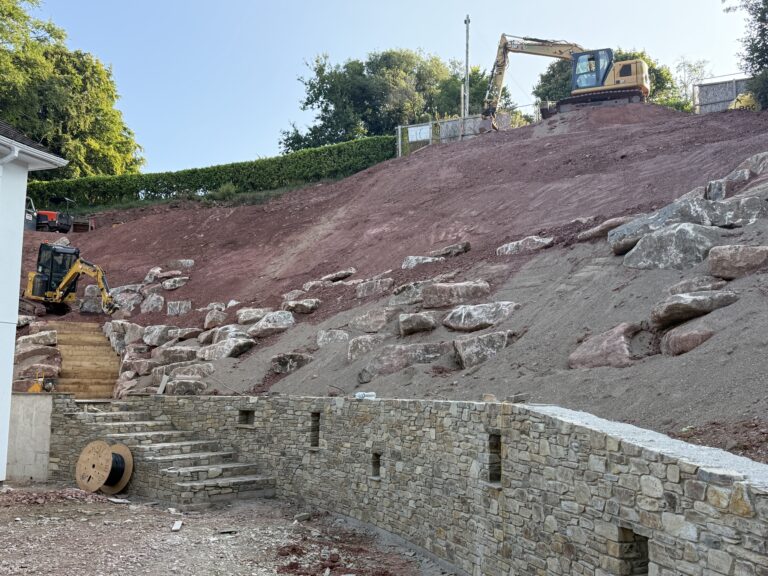 Long reach excavator and stone faced retaining wall