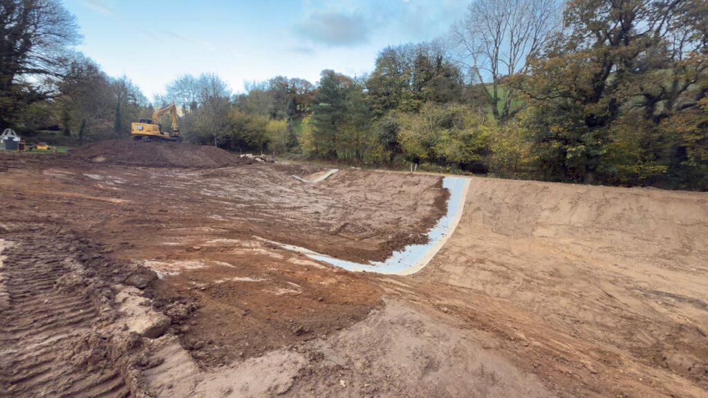 Wildlife pool with the liner installed and the first layers of soil being added for backfilling