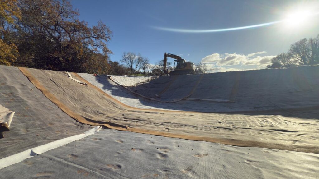 Close-up view of the wildlife pool’s fitted liner showing the material laid smoothly in the excavated shape